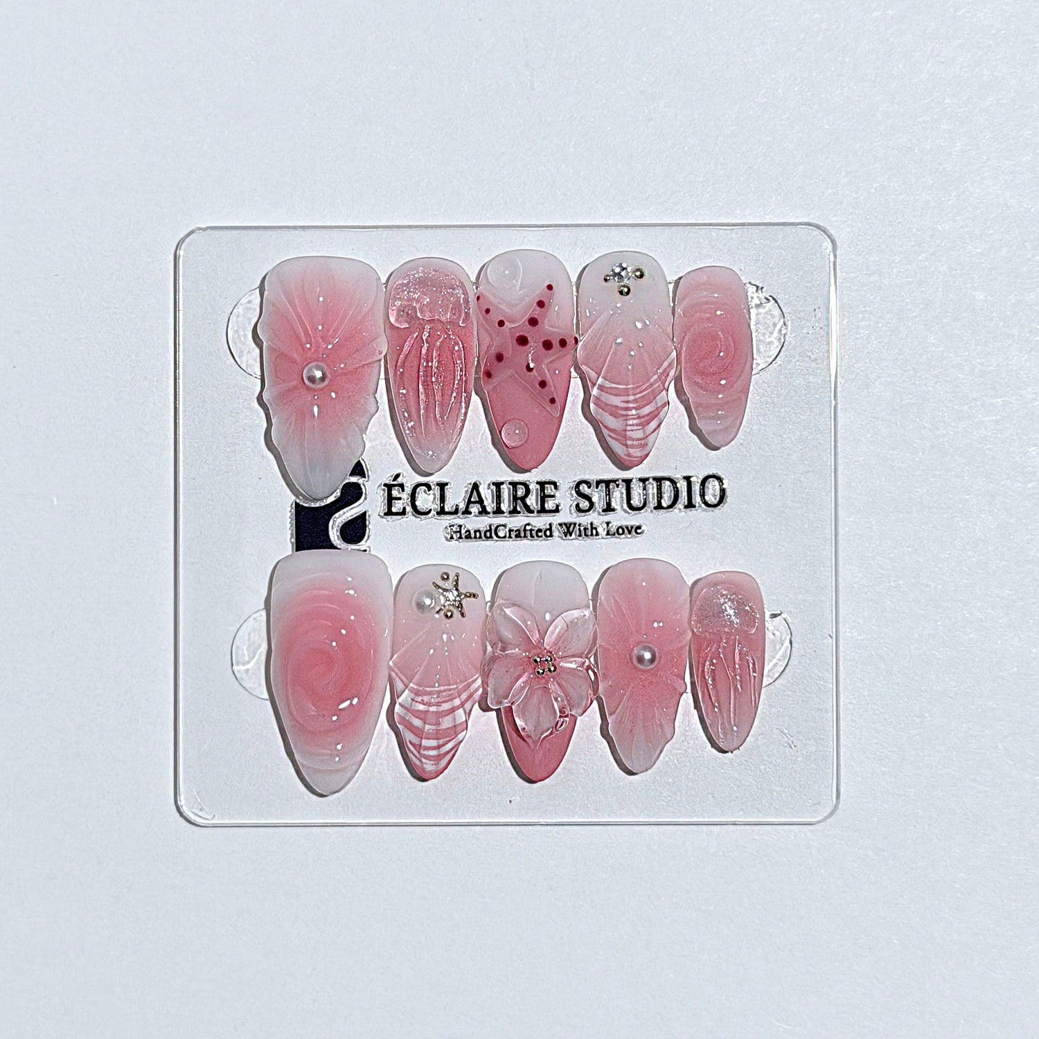 Luxury press-on nails featuring a soft blush pink ombre base with white French tips, a translucent 3D jellyfish, a sculpted pink starfish, and a clear 3D glass flower with a pearl center.