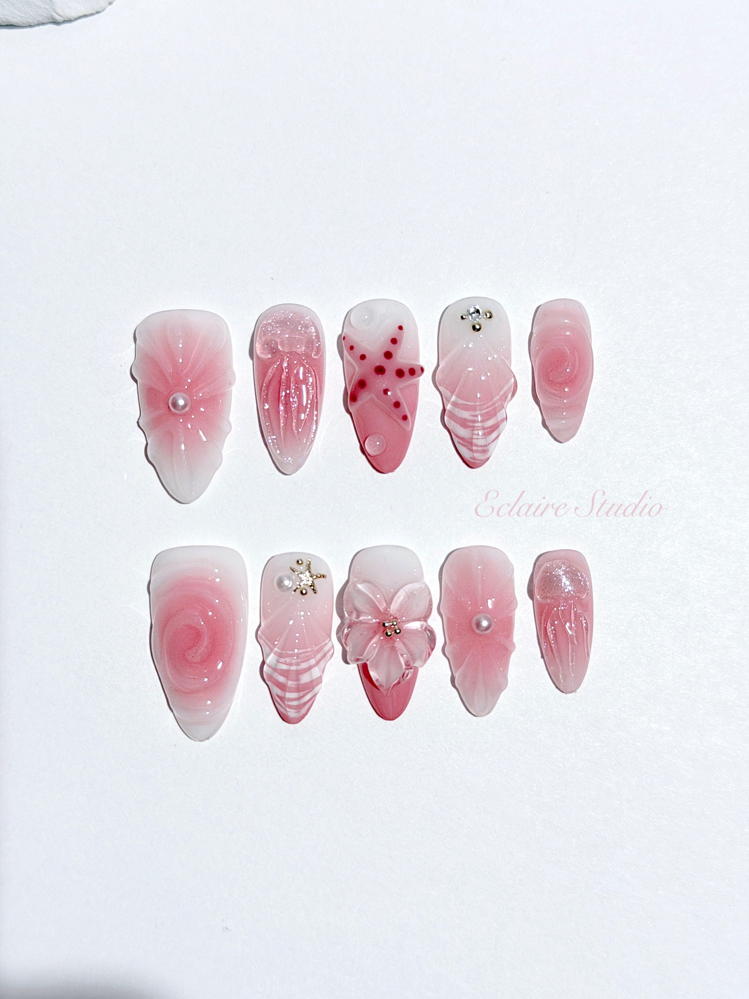 Luxury press-on nails featuring a soft blush pink ombre base with white French tips, a translucent 3D jellyfish, a sculpted pink starfish, and a clear 3D glass flower with a pearl center.