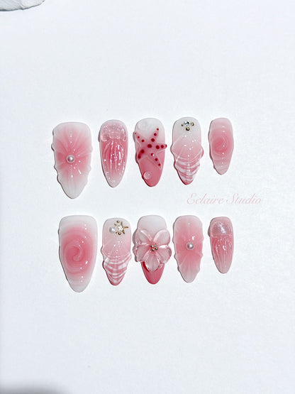 Luxury press-on nails featuring a soft blush pink ombre base with white French tips, a translucent 3D jellyfish, a sculpted pink starfish, and a clear 3D glass flower with a pearl center.