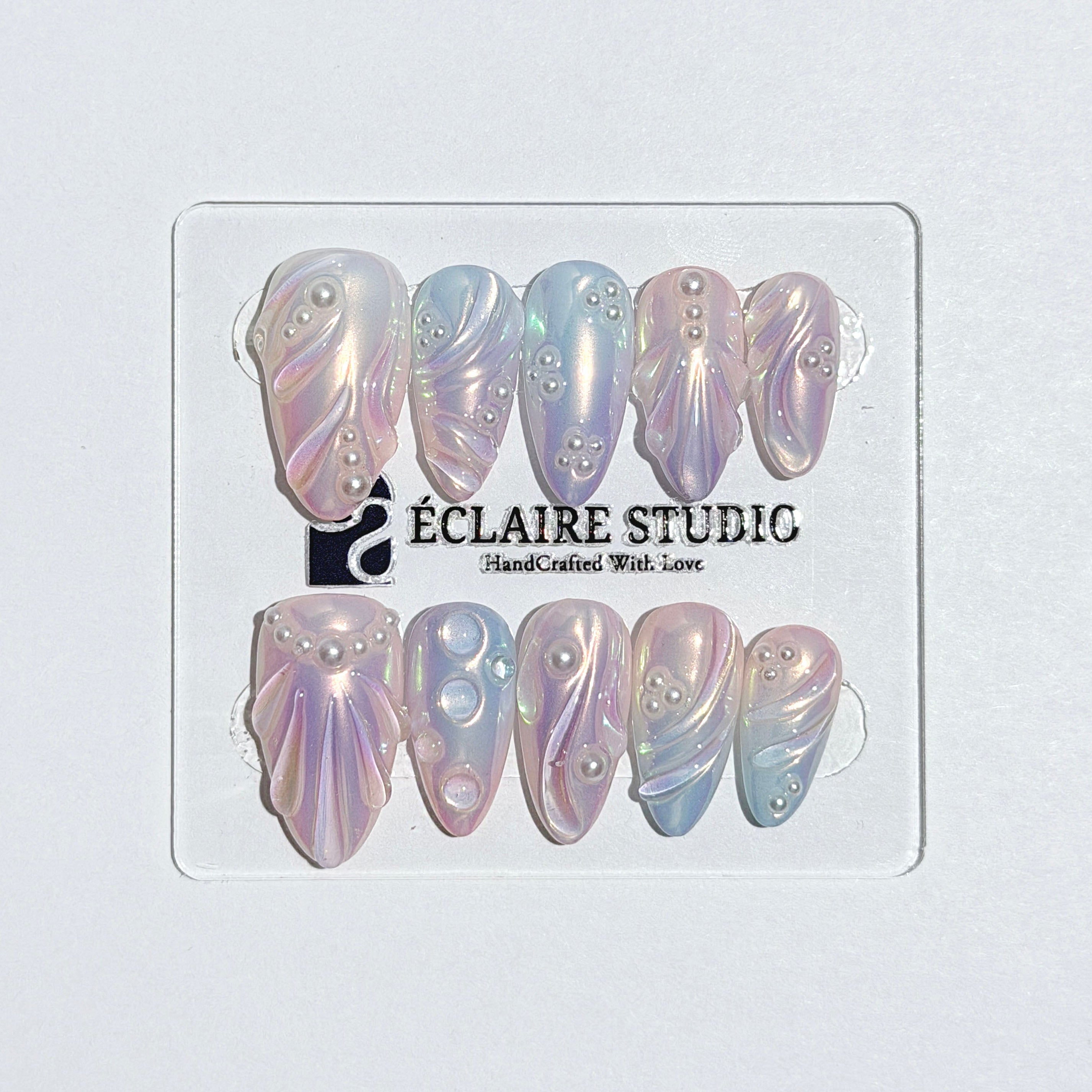 Handcrafted luxury press-on nails in a medium almond shape featuring an iridescent multi-toned glazed finish with 3D sculpted shell ridges and delicate mini pearls.