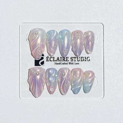 Handcrafted luxury press-on nails in a medium almond shape featuring an iridescent multi-toned glazed finish with 3D sculpted shell ridges and delicate mini pearls.