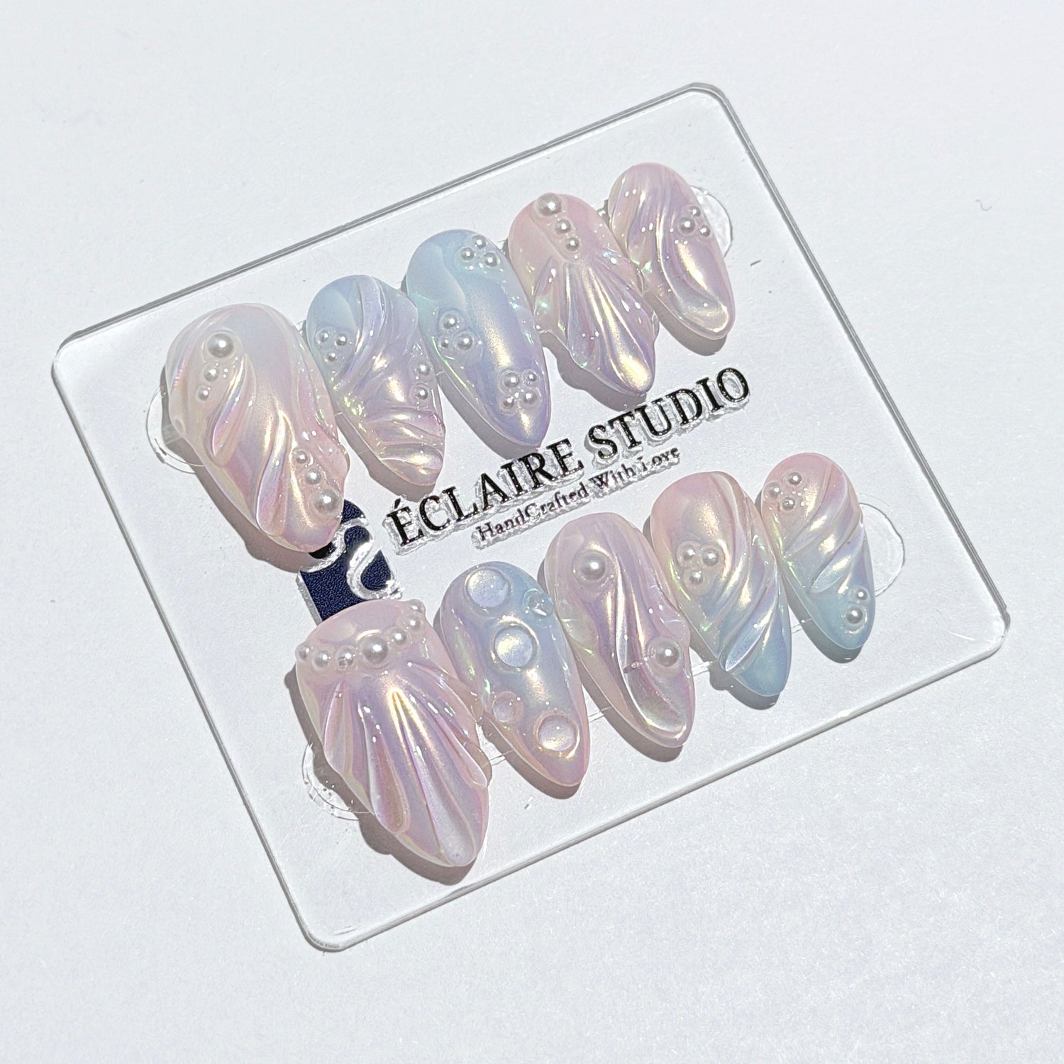 Handcrafted luxury press-on nails in a medium almond shape featuring an iridescent multi-toned glazed finish with 3D sculpted shell ridges and delicate mini pearls.
