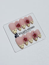 Luxury medium almond press-on nails featuring sheer pink bases with vintage cream French tips, burgundy polka dots, and hand-sculpted 3D burgundy flowers with gold bead centers.