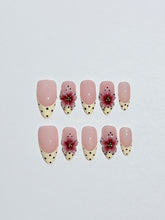 Luxury medium almond press-on nails featuring sheer pink bases with vintage cream French tips, burgundy polka dots, and hand-sculpted 3D burgundy flowers with gold bead centers.