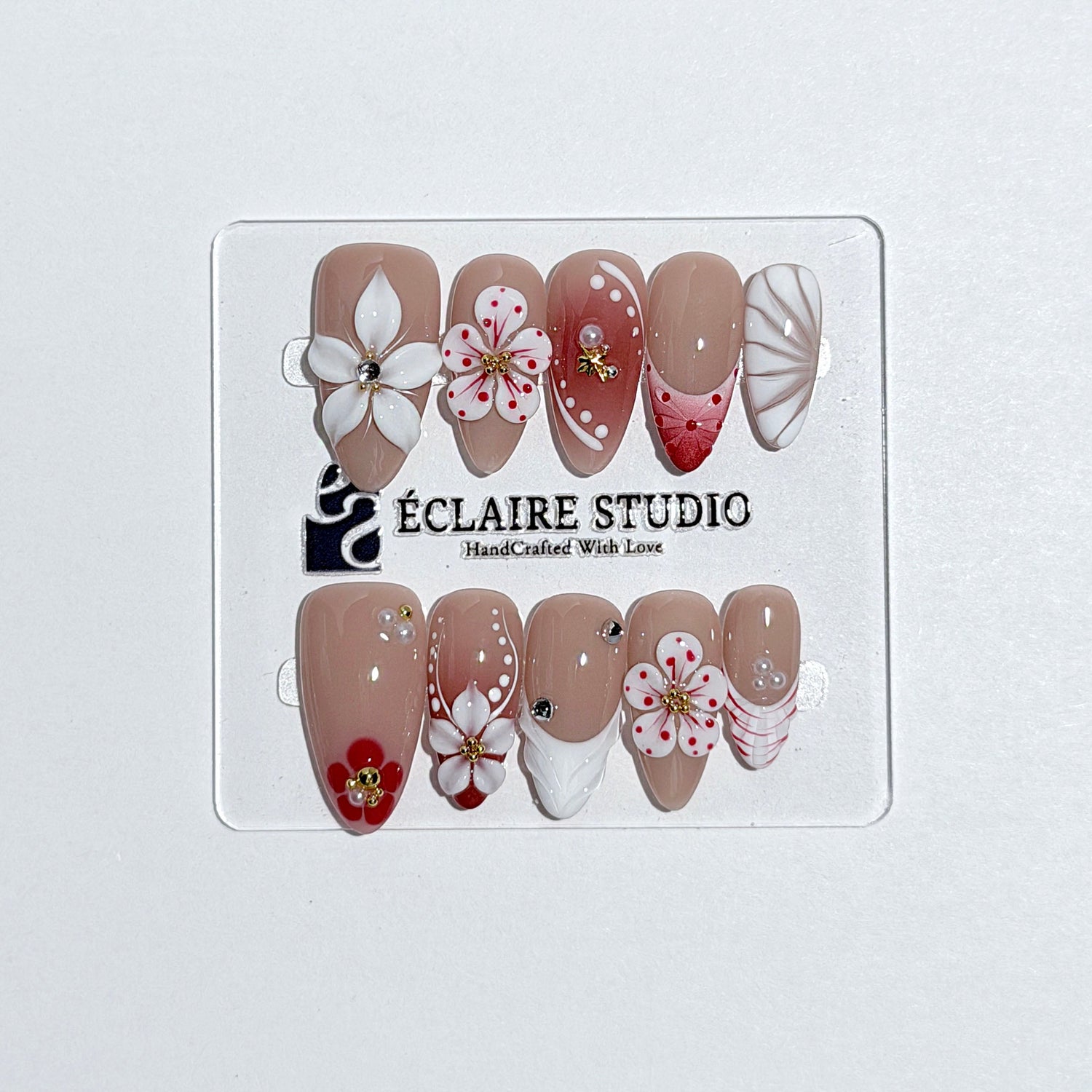 Rouge press-on nails with red linework and 3D white florals on a nude base – Éclaire Studio