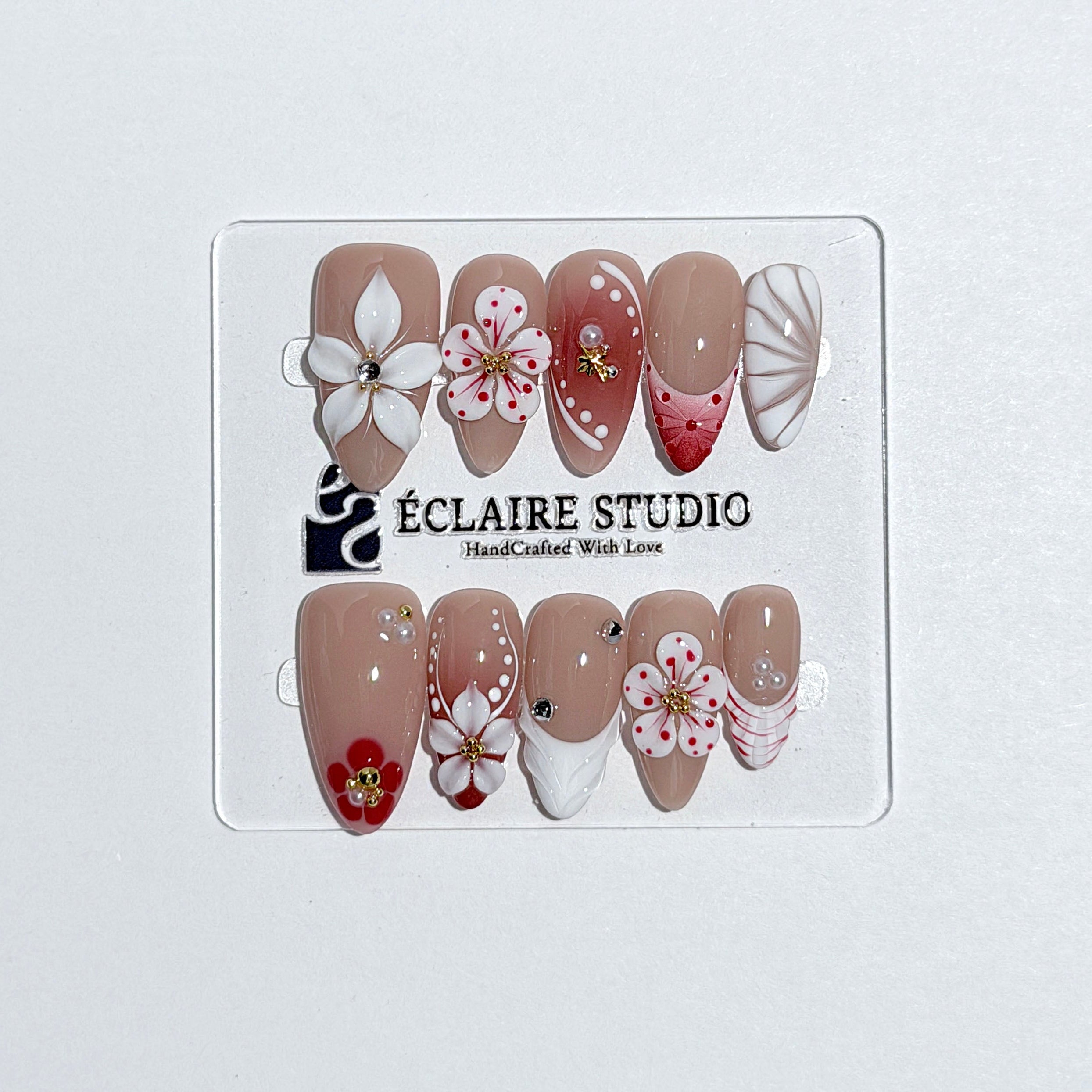 Rouge press-on nails with red linework and 3D white florals on a nude base – Éclaire Studio