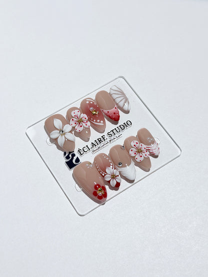 Rouge press-on nails with red linework and 3D white florals on a nude base – Éclaire Studio