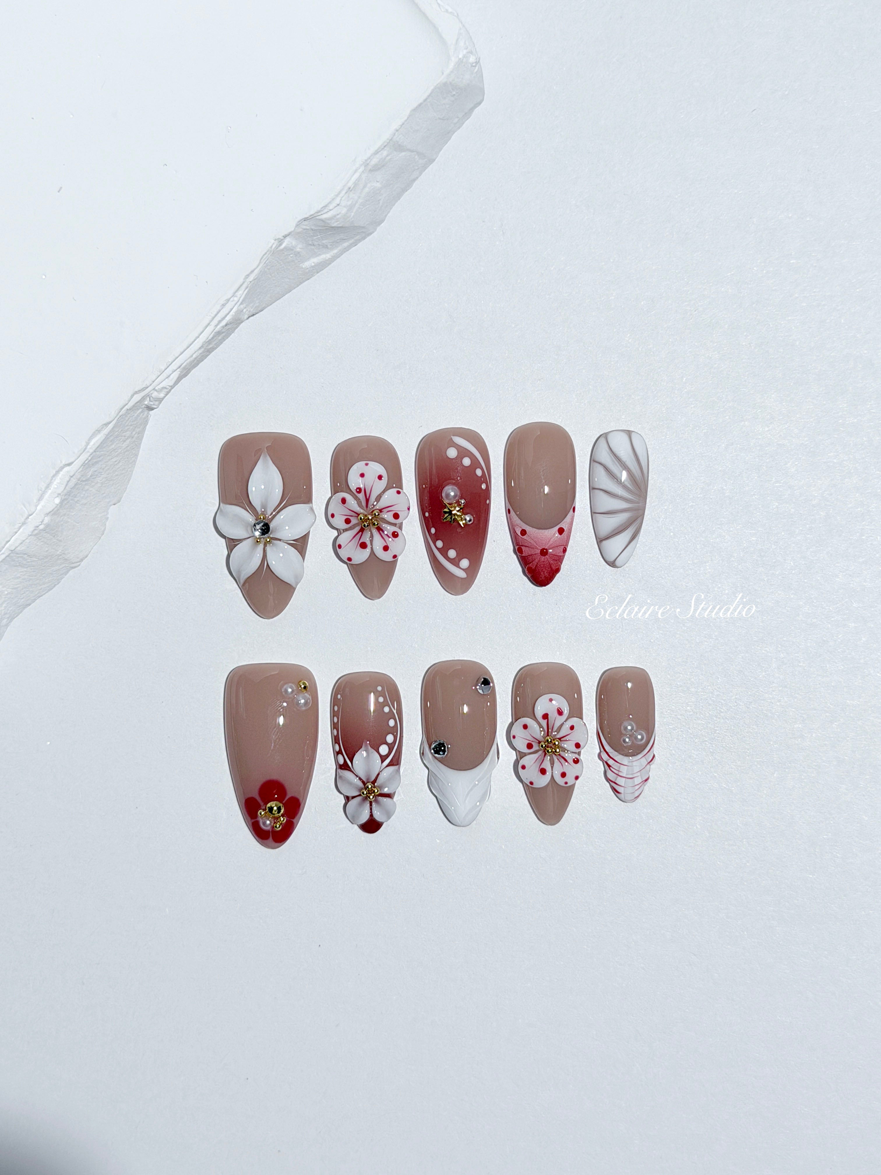 Rouge press-on nails with red linework and 3D white florals on a nude base – Éclaire Studio