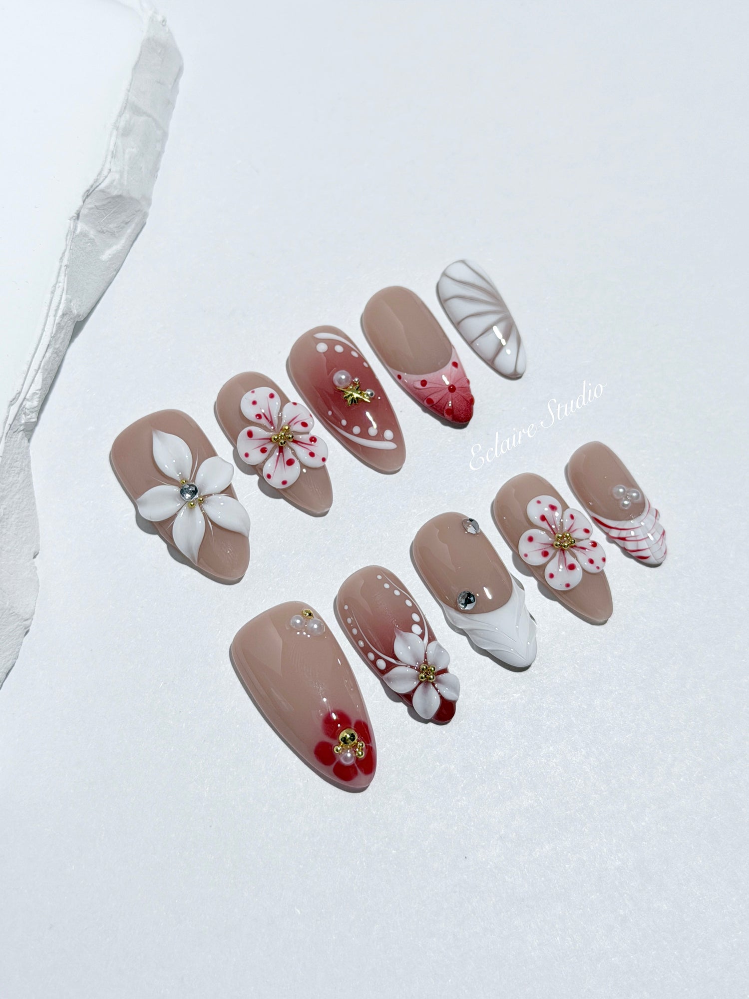 Rouge press-on nails with red linework and 3D white florals on a nude base – Éclaire Studio