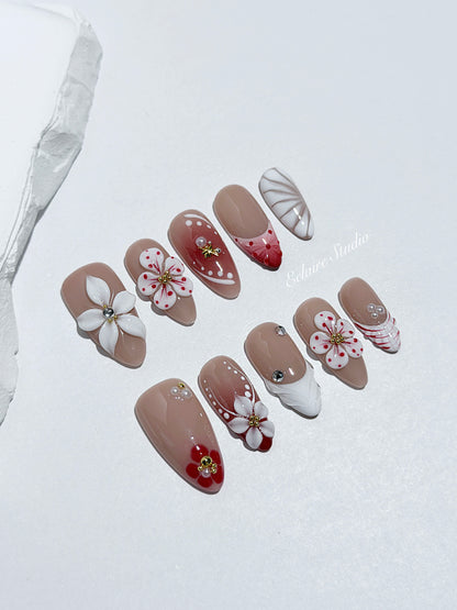 Rouge press-on nails with red linework and 3D white florals on a nude base – Éclaire Studio