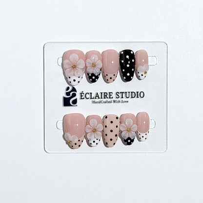 Eclaire Nail Studio 3D Floral Polka dot pink base with alternating black and white polka dot French tips, and hand-sculpted 3D frosted white flowers with gold bead centers, Short Almond