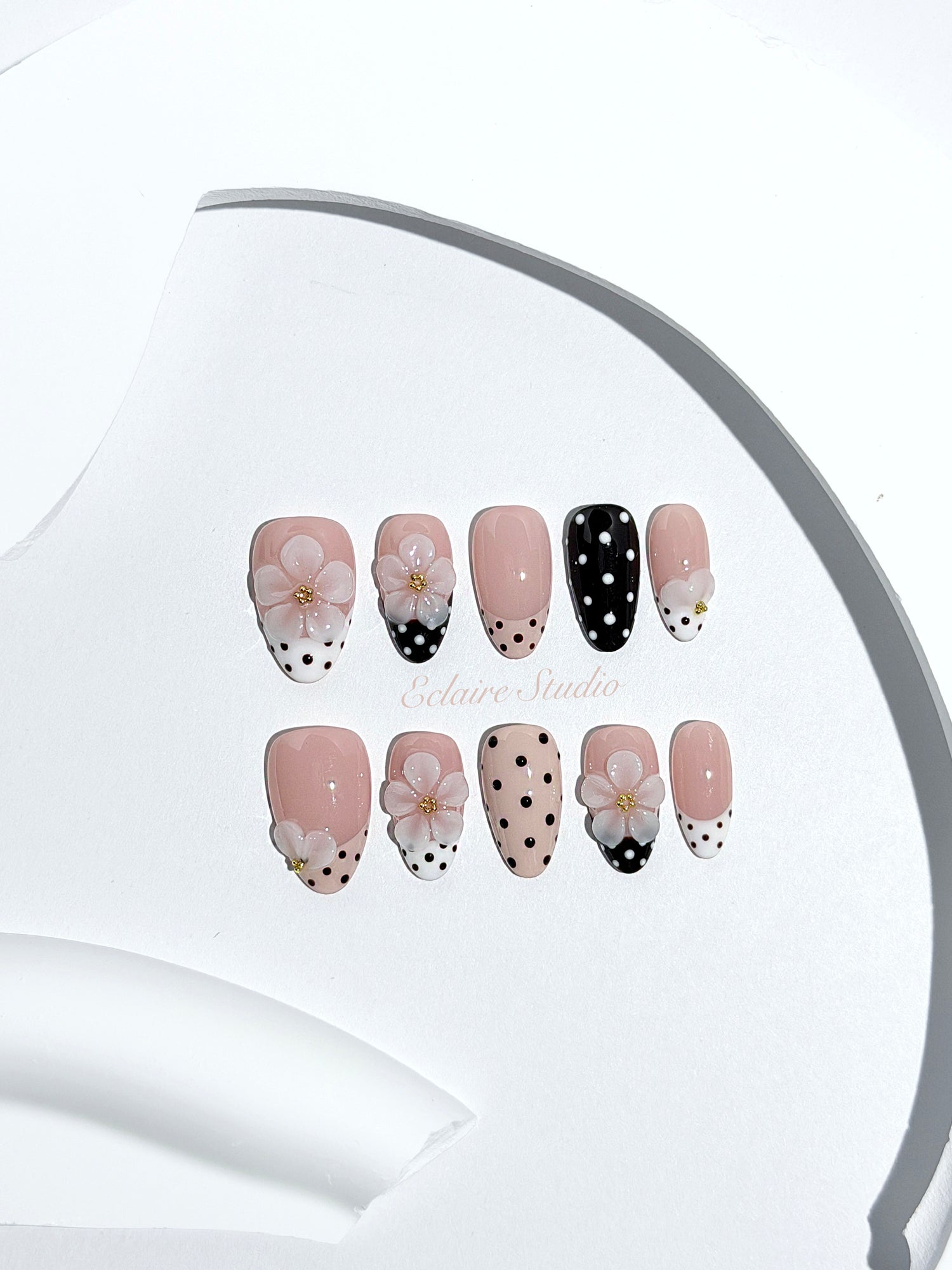 Eclaire Nail Studio 3D Floral Polka dot pink base with alternating black and white polka dot French tips, and hand-sculpted 3D frosted white flowers with gold bead centers, Short Almond