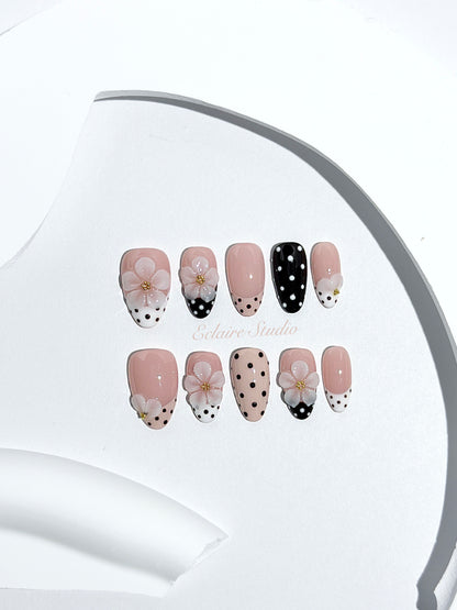 Eclaire Nail Studio 3D Floral Polka dot pink base with alternating black and white polka dot French tips, and hand-sculpted 3D frosted white flowers with gold bead centers, Short Almond