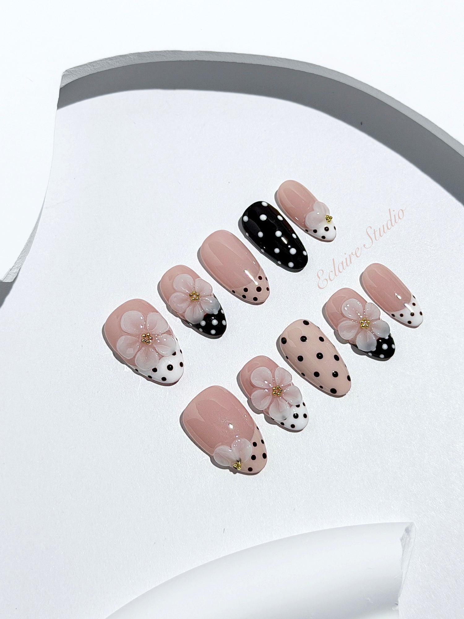 Eclaire Nail Studio 3D Floral Polka dot pink base with alternating black and white polka dot French tips, and hand-sculpted 3D frosted white flowers with gold bead centers, Short Almond