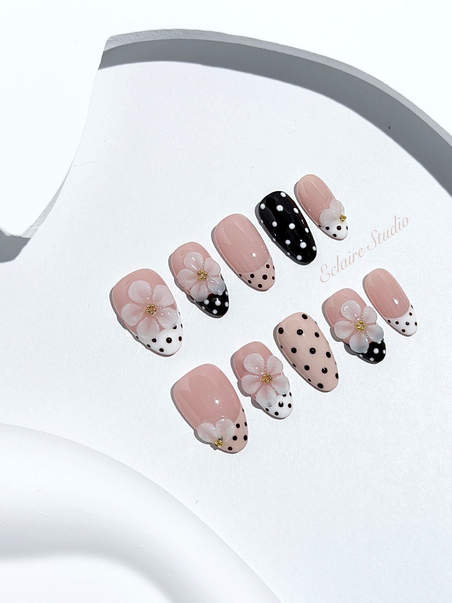 Eclaire Nail Studio 3D Floral Polka dot pink base with alternating black and white polka dot French tips, and hand-sculpted 3D frosted white flowers with gold bead centers, Short Almond
