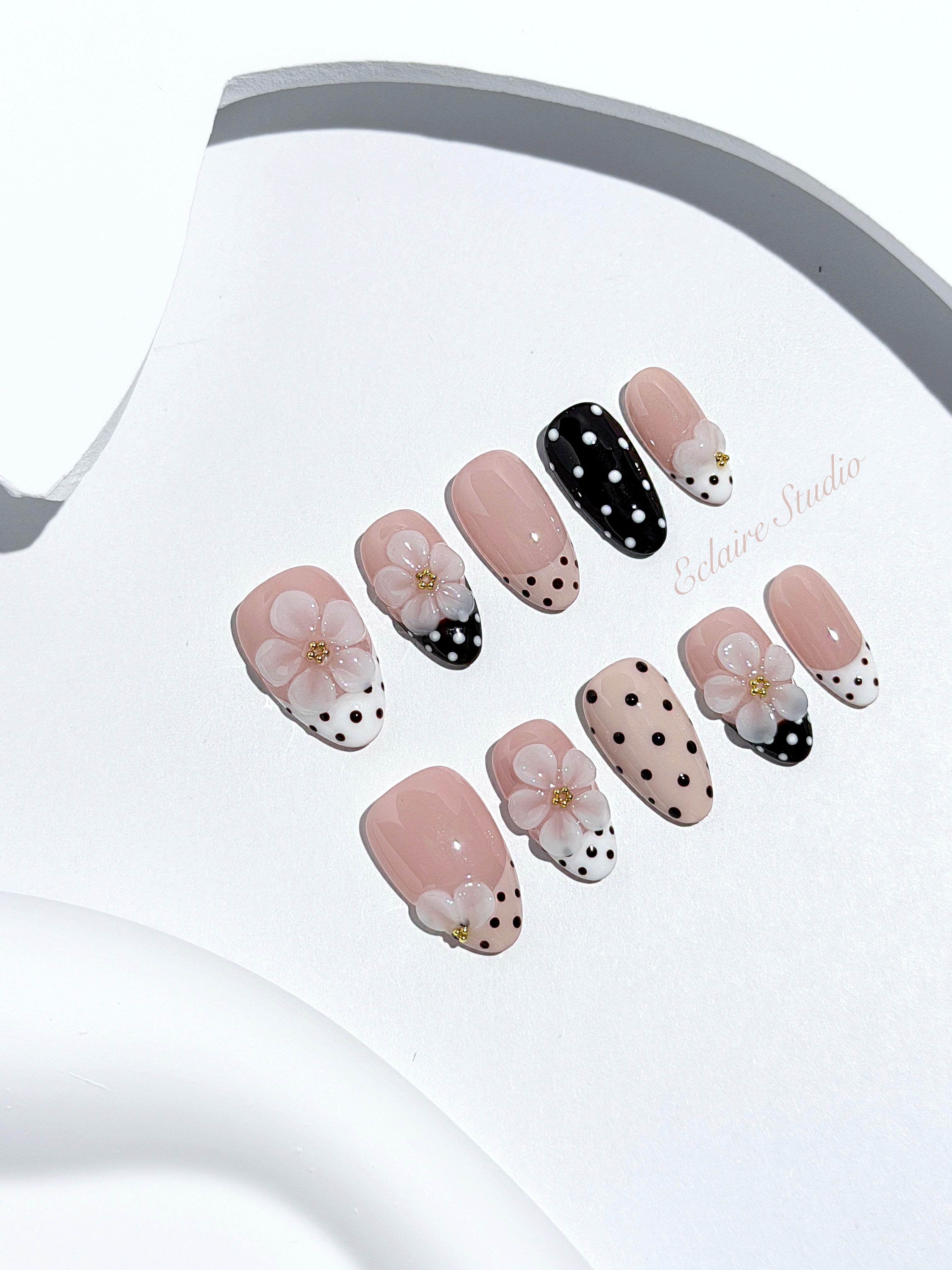 Eclaire Nail Studio 3D Floral Polka dot pink base with alternating black and white polka dot French tips, and hand-sculpted 3D frosted white flowers with gold bead centers, Short Almond
