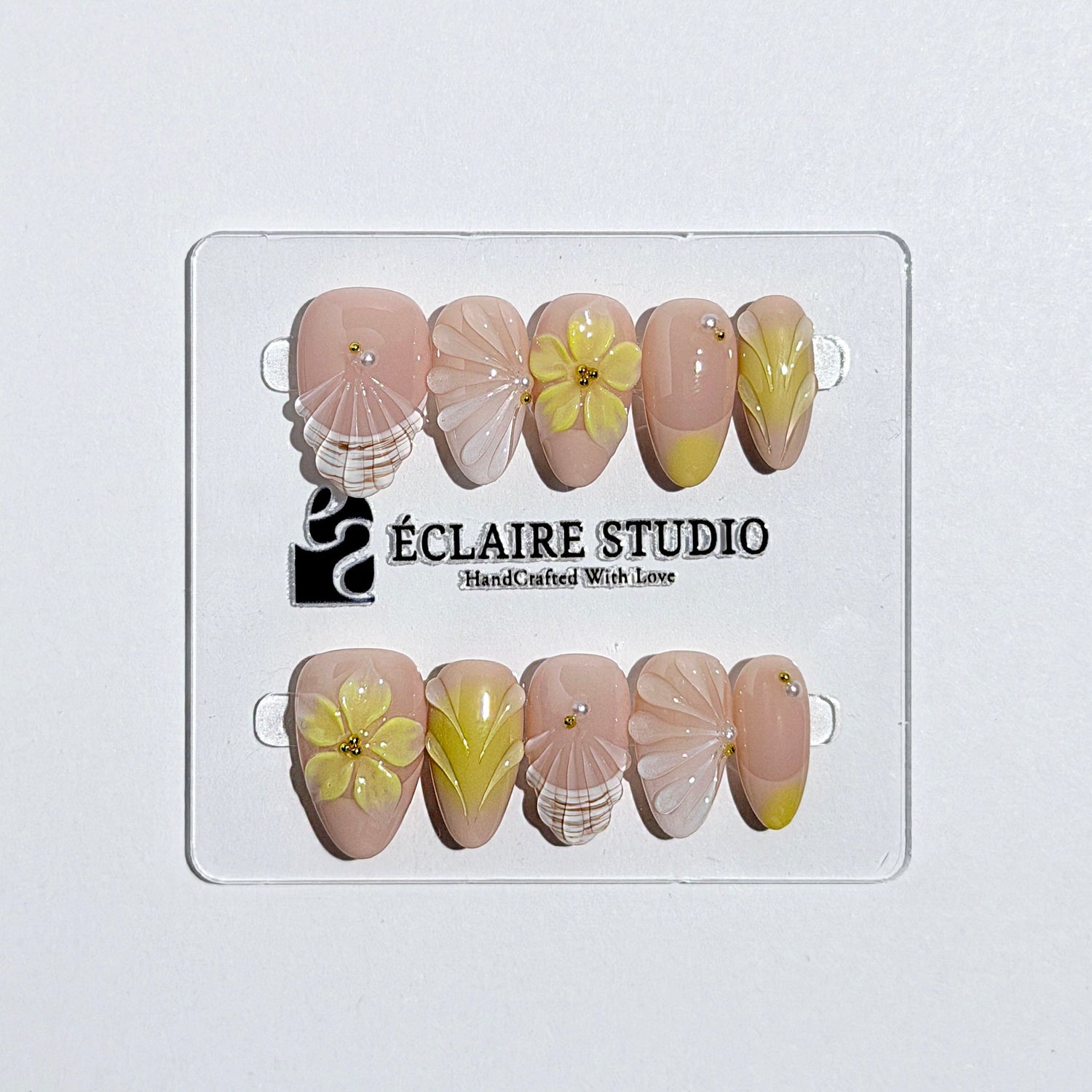Eclaire Studio Yellow Summer short almond press-on nails featuring a sheer nude base with yellow French tips, hand-sculpted 3D flowers, frosted 3D seashells