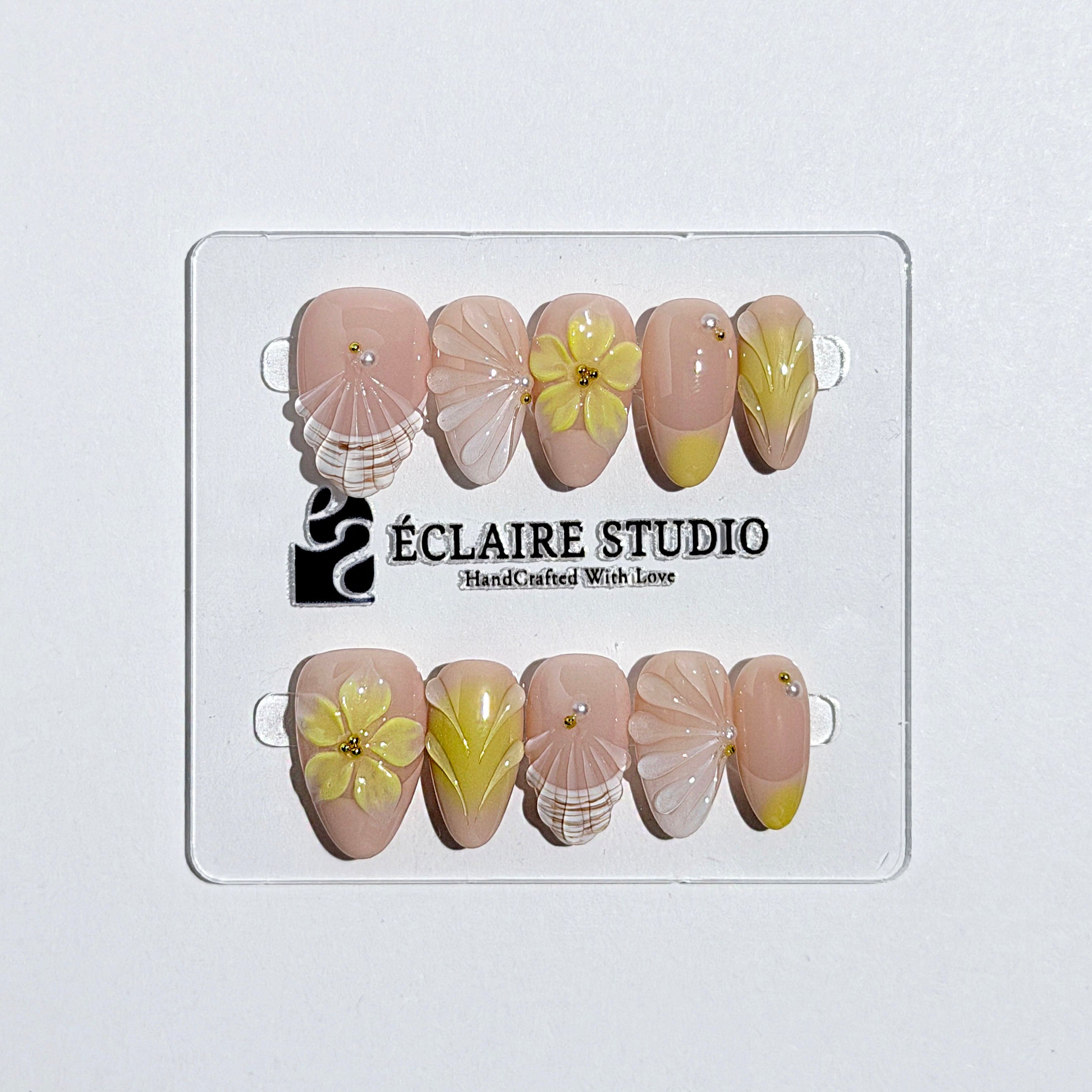 Eclaire Studio Yellow Summer short almond press-on nails featuring a sheer nude base with yellow French tips, hand-sculpted 3D flowers, frosted 3D seashells
