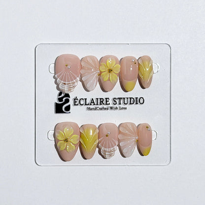 Eclaire Studio Yellow Summer short almond press-on nails featuring a sheer nude base with yellow French tips, hand-sculpted 3D flowers, frosted 3D seashells