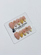 Summer Eclaire Nail Studio Luxury short almond press-on nails featuring a sheer nude base with butter yellow French tips, hand-sculpted 3D pink starfish, amber-tinted 3D seashells, and flowers with gold accents.
