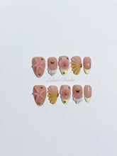 Summer Eclaire Nail Studio Luxury short almond press-on nails featuring a sheer nude base with butter yellow French tips, hand-sculpted 3D pink starfish, amber-tinted 3D seashells, and flowers with gold accents.