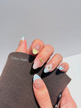 Artisanal resort-style press-on nails with a sheer nude base, pastel blue and yellow striped French tips, 3D sculpted flowers, and gold starfish charms with mini pearls.