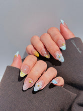 Artisanal resort-style press-on nails with a sheer nude base, pastel blue and yellow striped French tips, 3D sculpted flowers, and gold starfish charms with mini pearls.