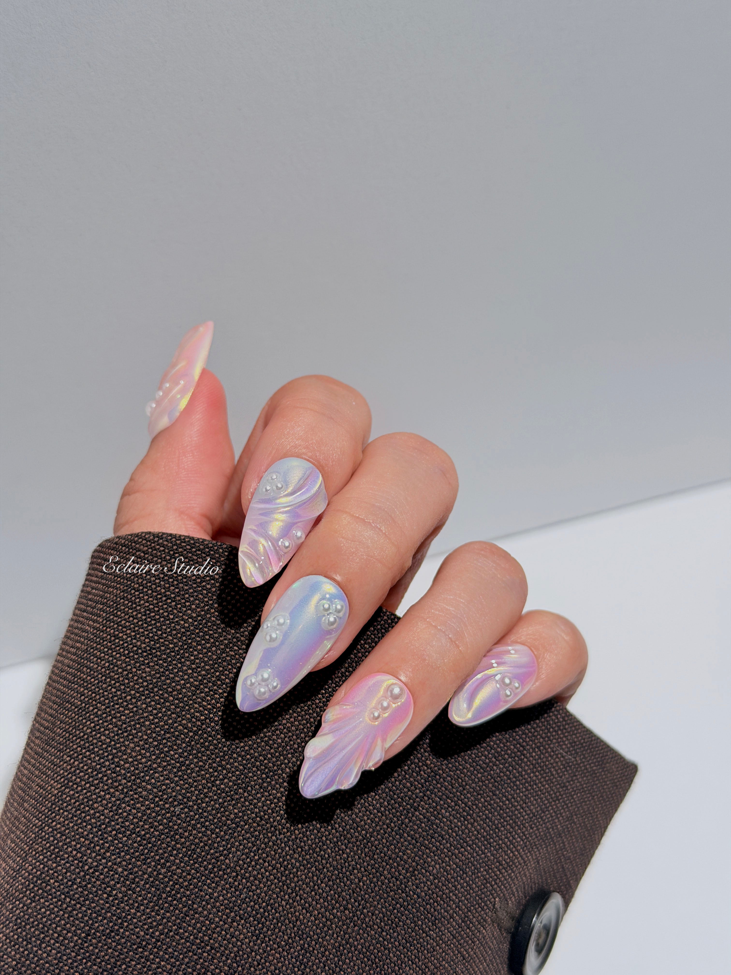 Handcrafted luxury press-on nails in a medium almond shape featuring an iridescent multi-toned glazed finish with 3D sculpted shell ridges and delicate mini pearls.