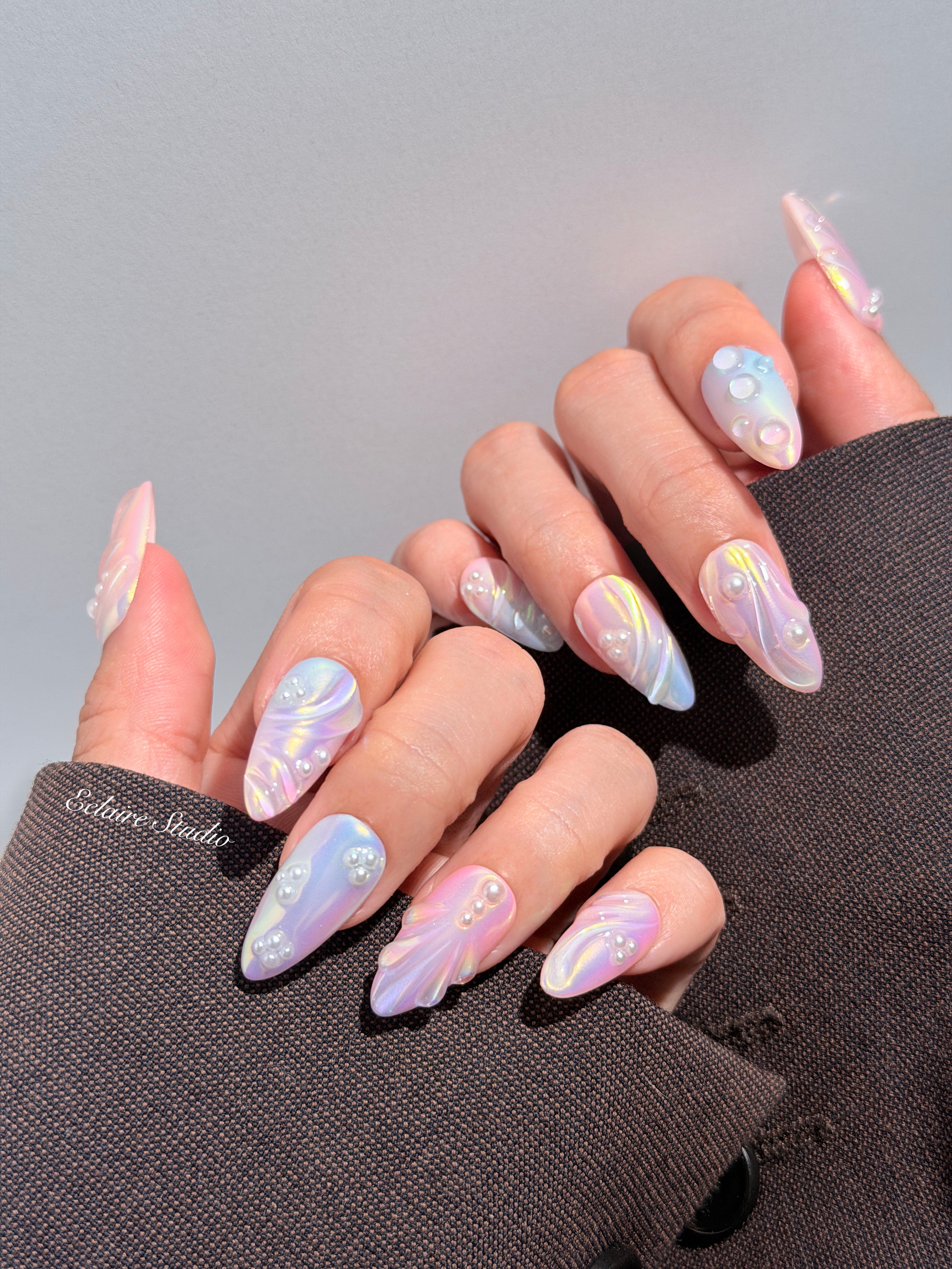 Handcrafted luxury press-on nails in a medium almond shape featuring an iridescent multi-toned glazed finish with 3D sculpted shell ridges and delicate mini pearls.