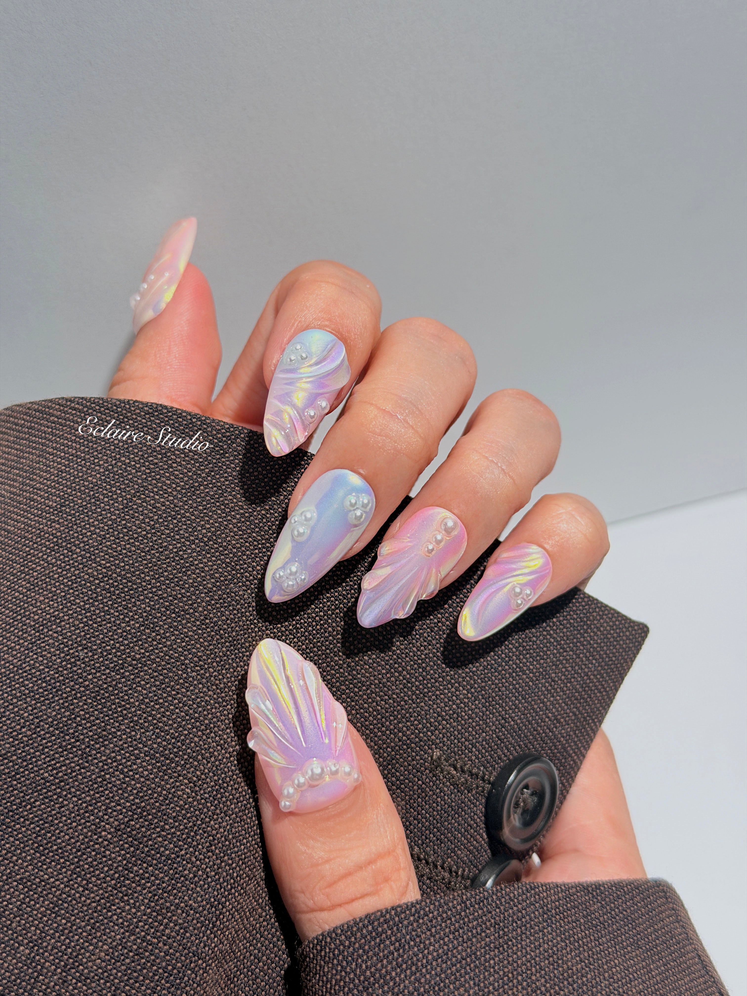 Handcrafted luxury press-on nails in a medium almond shape featuring an iridescent multi-toned glazed finish with 3D sculpted shell ridges and delicate mini pearls.