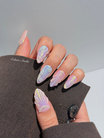 Handcrafted luxury press-on nails in a medium almond shape featuring an iridescent multi-toned glazed finish with 3D sculpted shell ridges and delicate mini pearls.