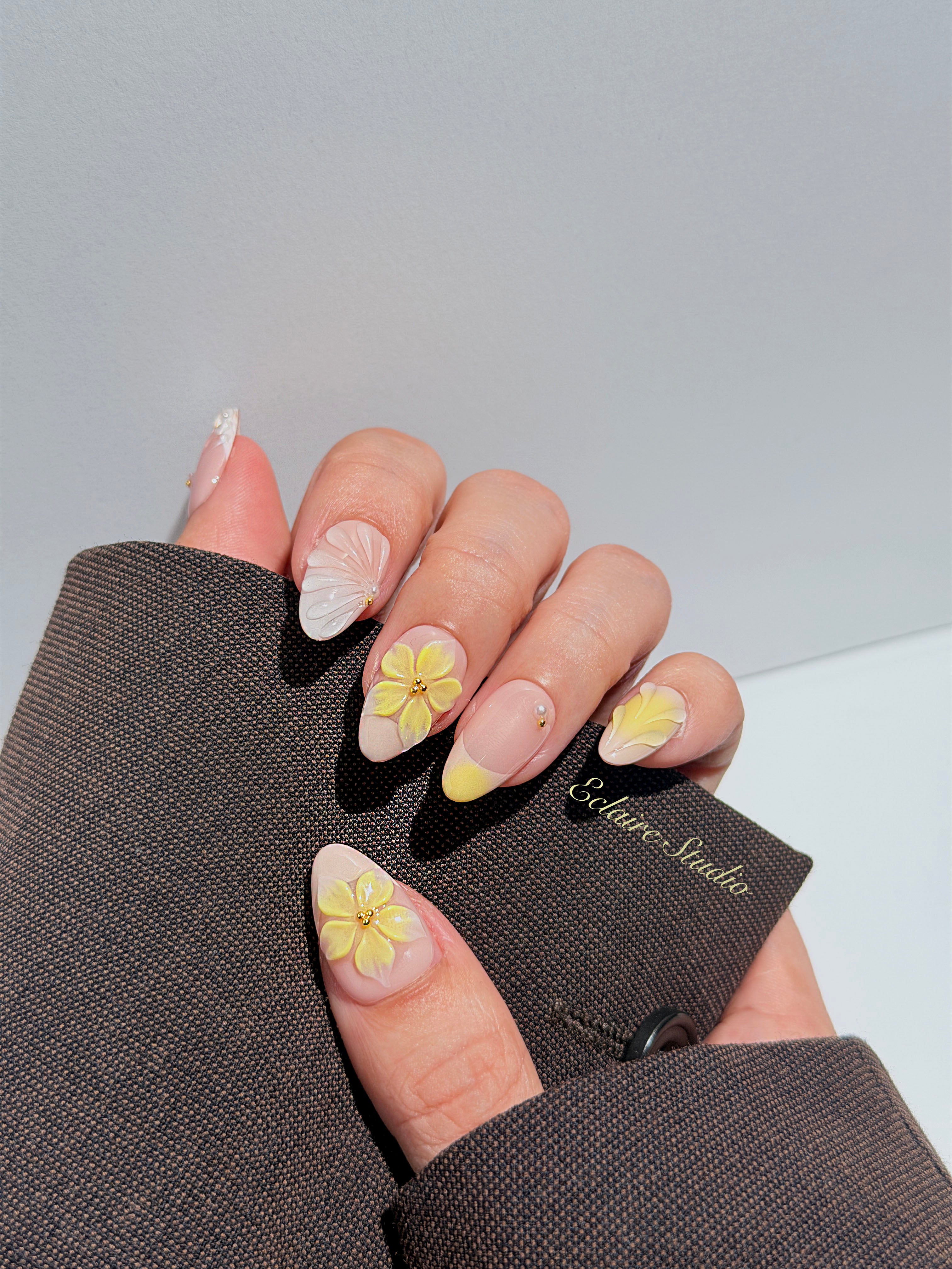 Eclaire Studio Yellow Summer short almond press-on nails featuring a sheer nude base with yellow French tips, hand-sculpted 3D flowers, frosted 3D seashells