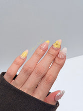 Eclaire Studio Yellow Summer short almond press-on nails featuring a sheer nude base with yellow French tips, hand-sculpted 3D flowers, frosted 3D seashells