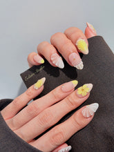 Eclaire Studio Yellow Summer short almond press-on nails featuring a sheer nude base with yellow French tips, hand-sculpted 3D flowers, frosted 3D seashells