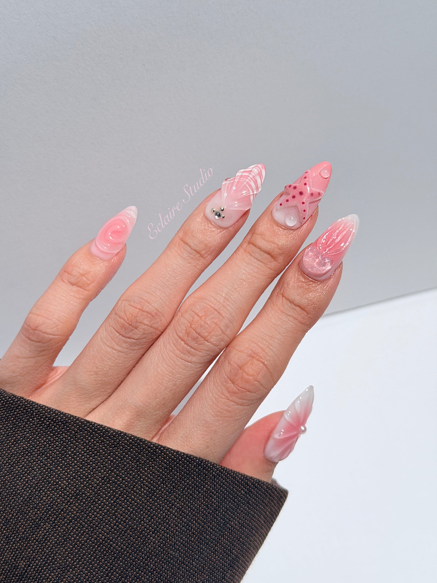 Luxury press-on nails featuring a soft blush pink ombre base with white French tips, a translucent 3D jellyfish, a sculpted pink starfish, and a clear 3D glass flower with a pearl center.