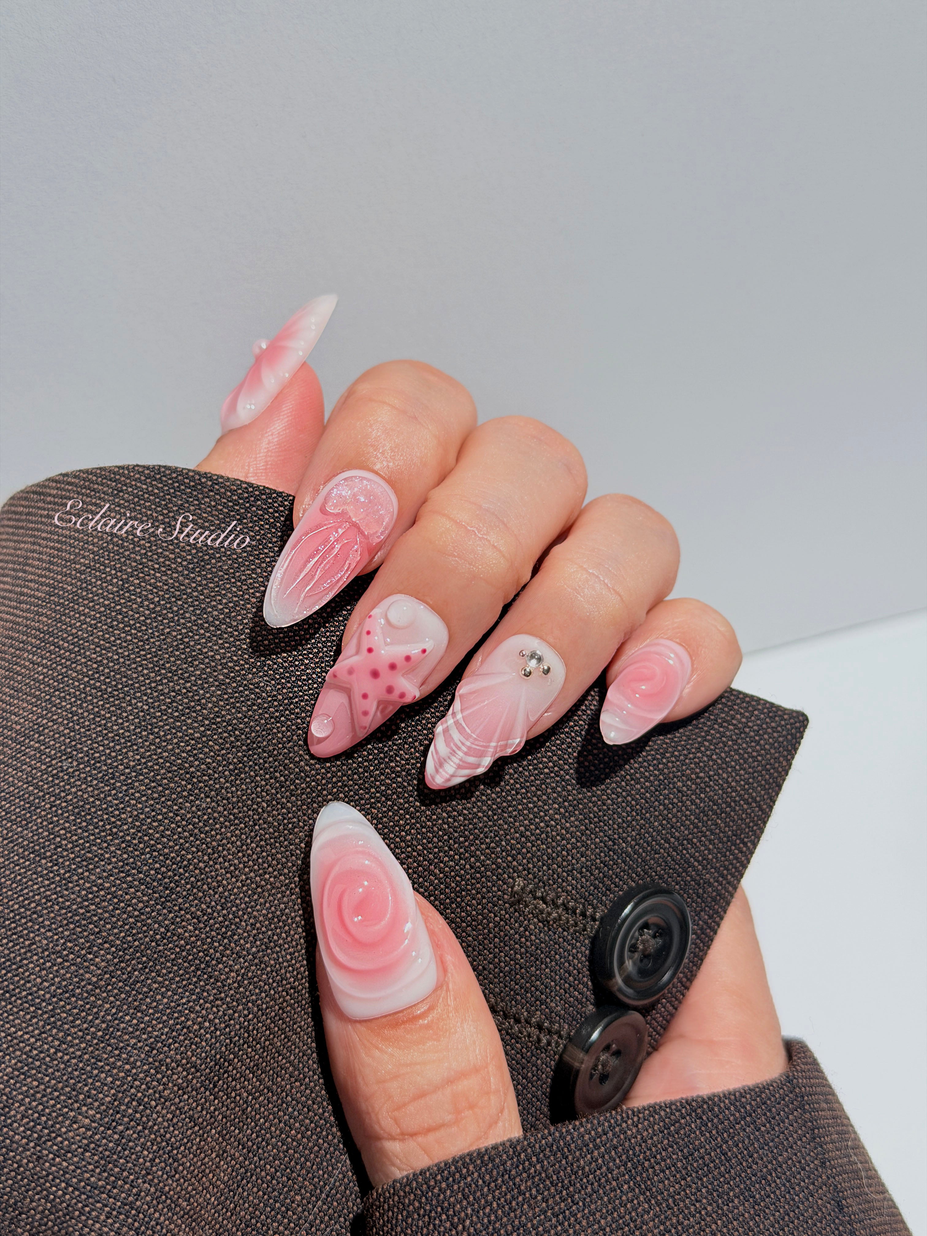 Luxury press-on nails featuring a soft blush pink ombre base with white French tips, a translucent 3D jellyfish, a sculpted pink starfish, and a clear 3D glass flower with a pearl center.