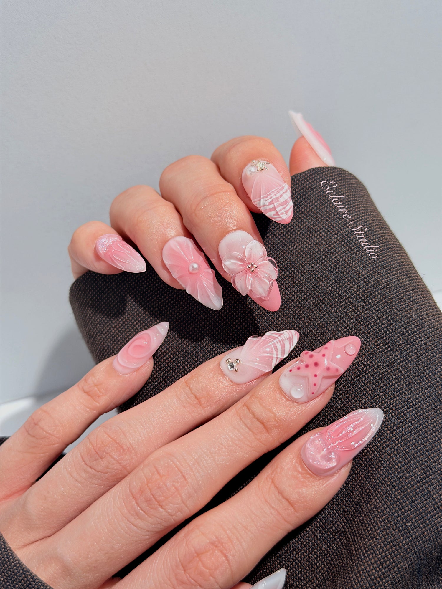 Luxury press-on nails featuring a soft blush pink ombre base with white French tips, a translucent 3D jellyfish, a sculpted pink starfish, and a clear 3D glass flower with a pearl center.