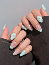Eclaire Nail Studio 3D Summer short almond press-on nails featuring a light aqua glazed base and peachy-nude accent nails with 3D sculpted ocean waves, 3D flowers, and seashell tips with mini pearls and gold stars.