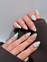 Eclaire Nail Studio 3D Summer short almond press-on nails featuring a light aqua glazed base and peachy-nude accent nails with 3D sculpted ocean waves, 3D flowers, and seashell tips with mini pearls and gold stars.