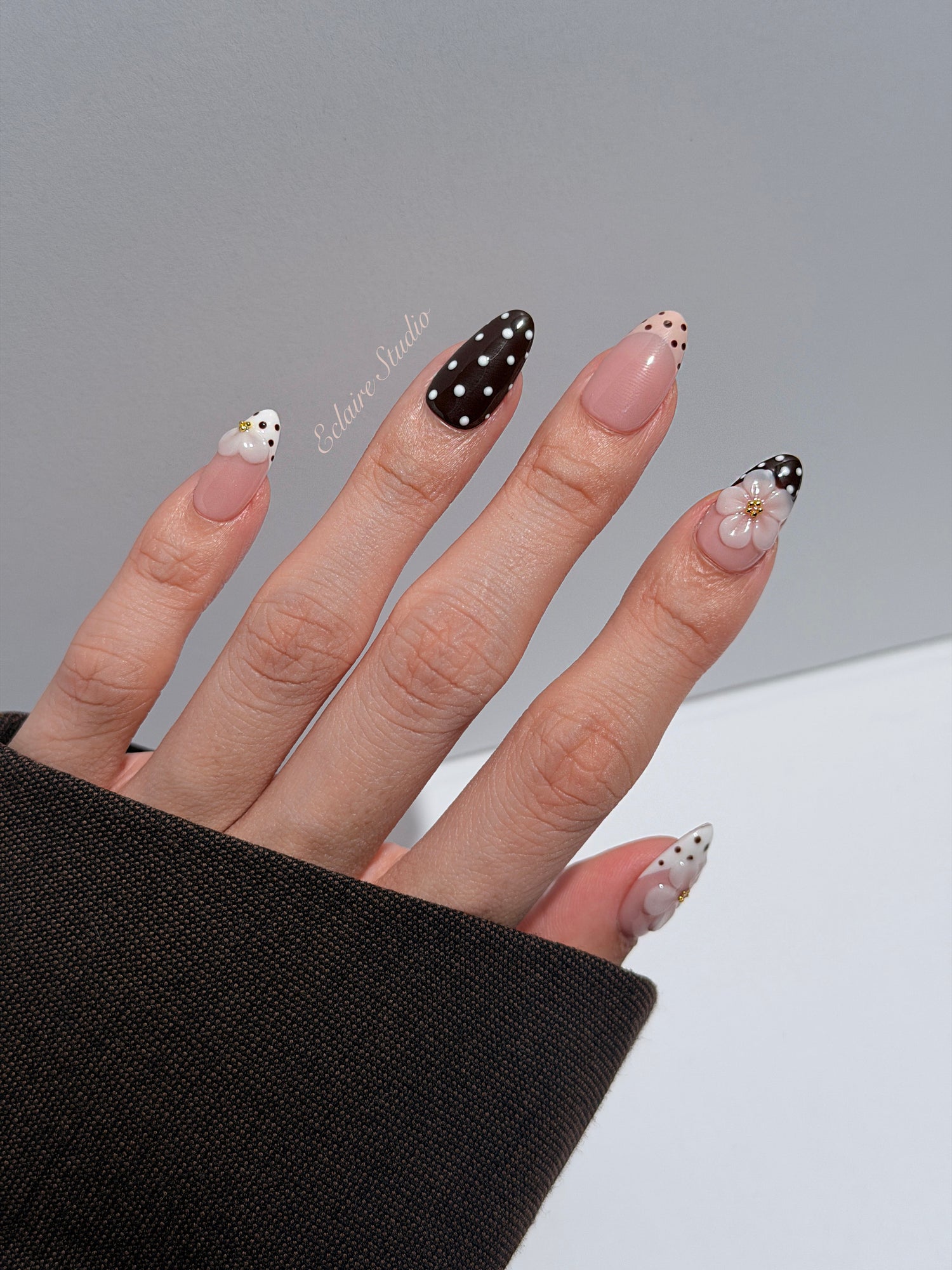 Eclaire Nail Studio 3D Floral Polka dot pink base with alternating black and white polka dot French tips, and hand-sculpted 3D frosted white flowers with gold bead centers, Short Almond