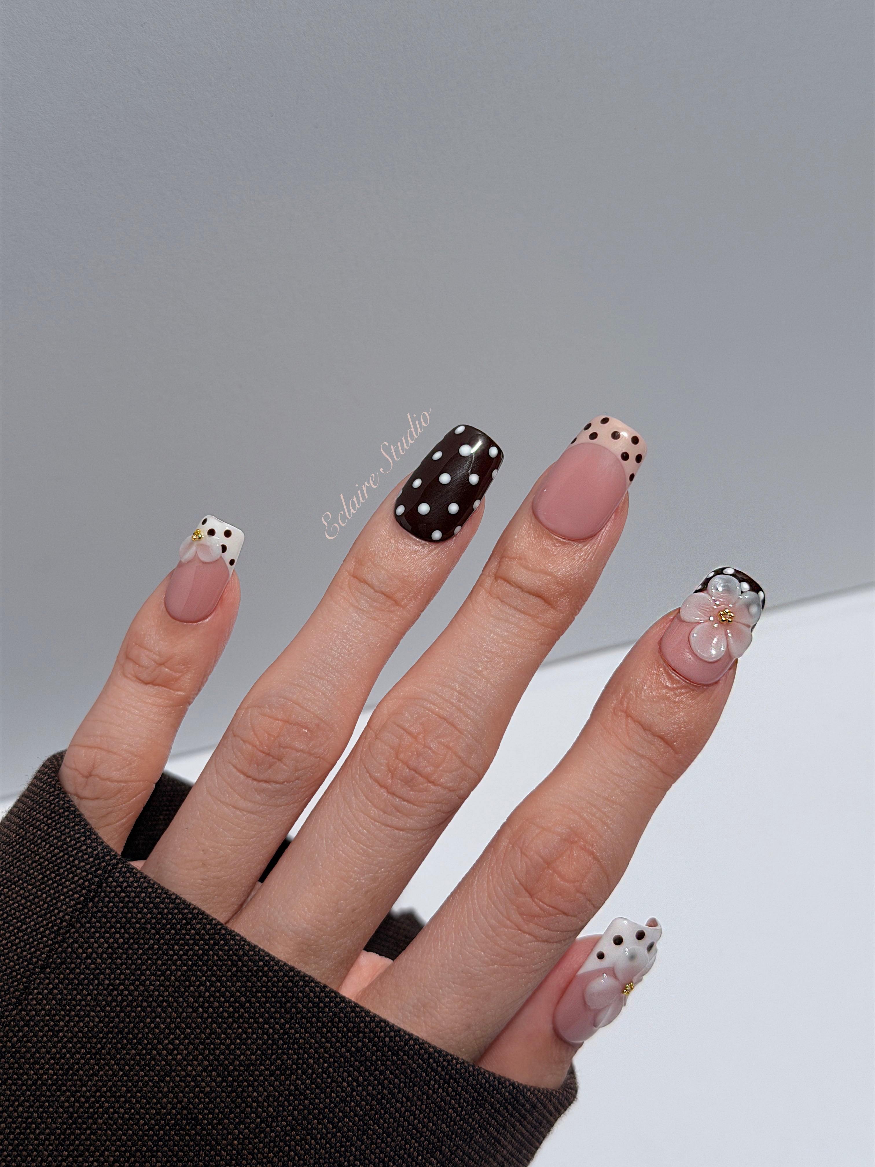 Eclaire Nail Studio 3D Floral Polka dot pink base with alternating black and white polka dot French tips, and hand-sculpted 3D frosted white flowers with gold bead centers, Medium Square