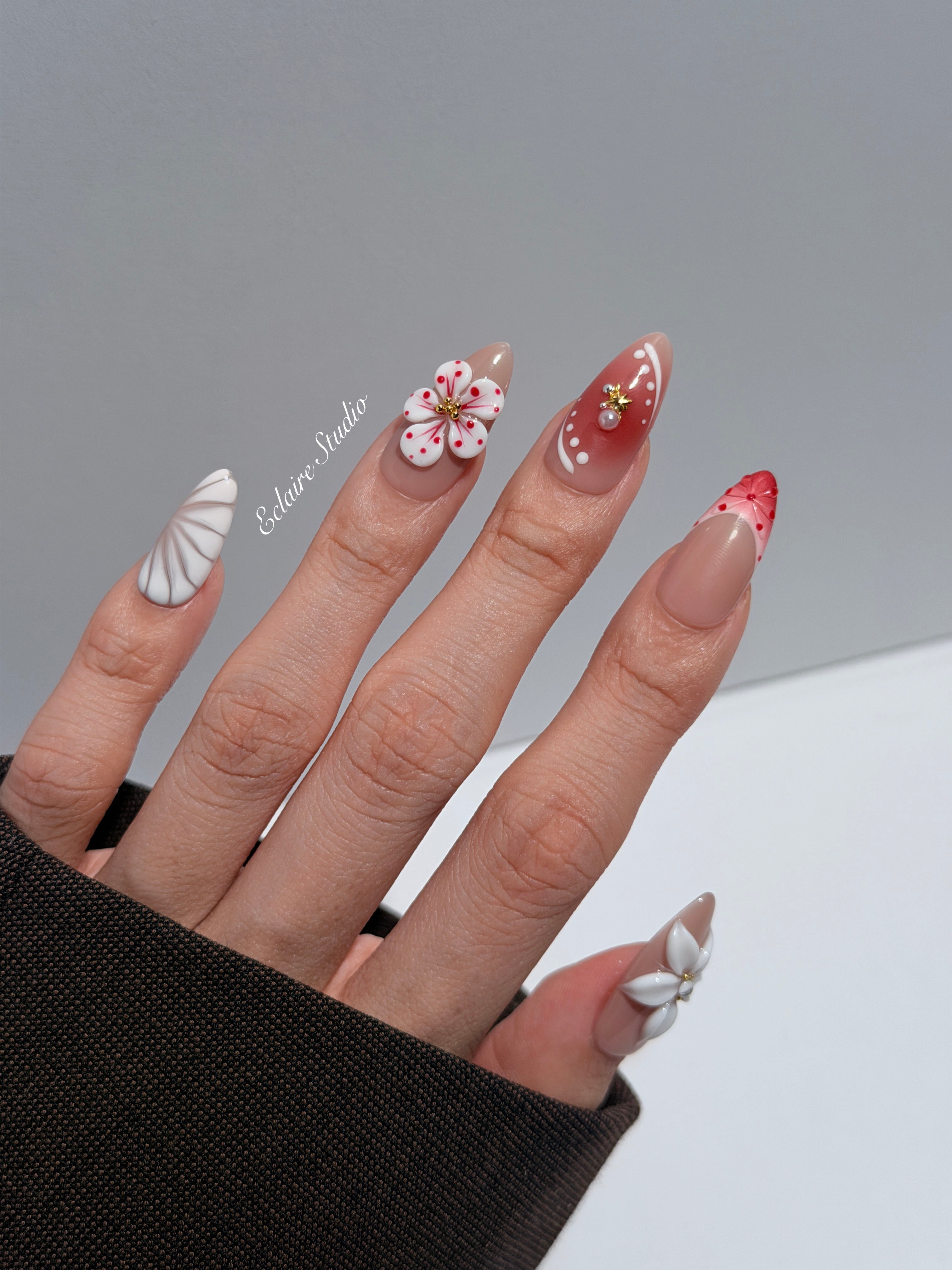Rouge press-on nails with red linework and 3D white florals on a nude base – Éclaire Studio