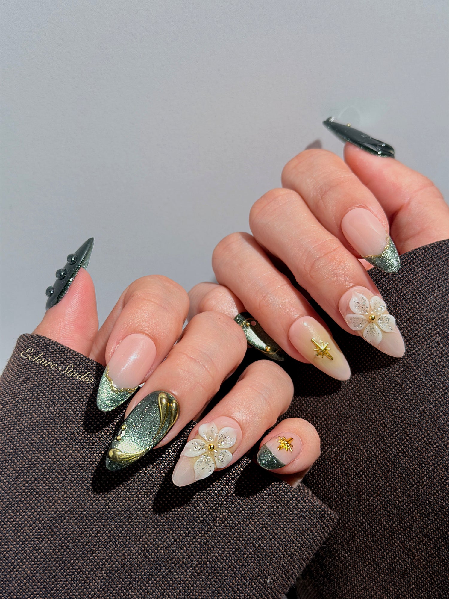 Bali Escape almond press-on nails with emerald cat-eye shimmer, 3D frosted flowers and gold accents – Éclaire Studio