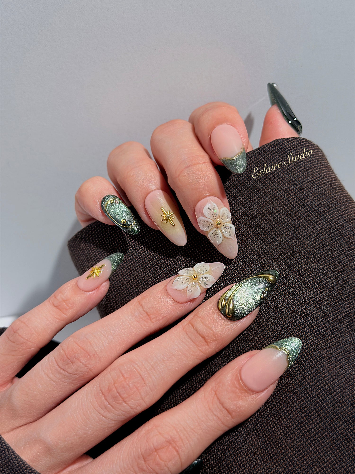 Bali Escape almond press-on nails with emerald cat-eye shimmer, 3D frosted flowers and gold accents – Éclaire Studio