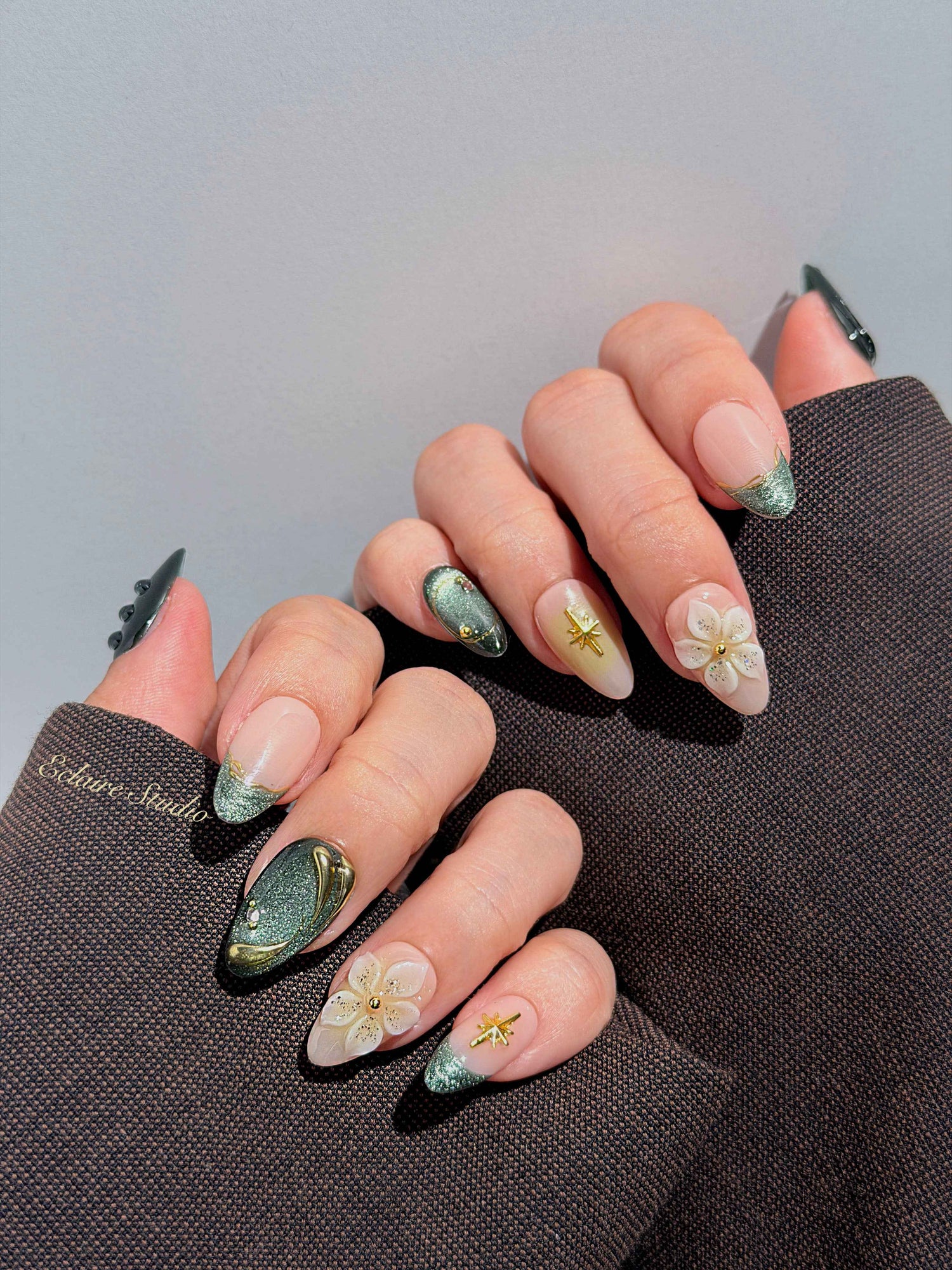 Bali Escape almond press-on nails with emerald cat-eye shimmer, 3D frosted flowers and gold accents – Éclaire Studio