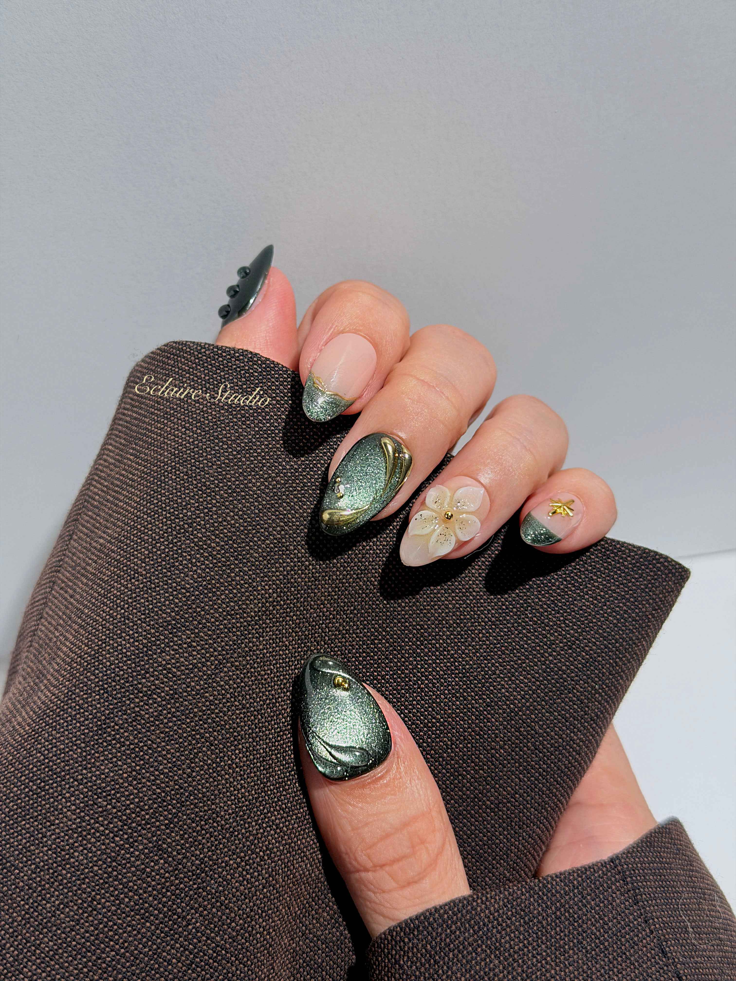 Bali Escape almond press-on nails with emerald cat-eye shimmer, 3D frosted flowers and gold accents – Éclaire Studio
