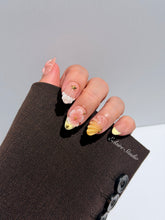 Summer Eclaire Nail Studio Luxury short almond press-on nails featuring a sheer nude base with butter yellow French tips, hand-sculpted 3D pink starfish, amber-tinted 3D seashells, and flowers with gold accents.
