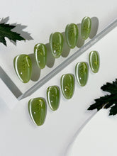 Green cat-eye press-on nails featuring layered ivy designs brushed with shiny green powder — Éclaire Nail Studio