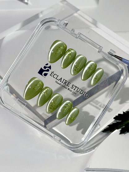 Green cat-eye press-on nails featuring layered ivy designs brushed with shiny green powder — Éclaire Nail Studio